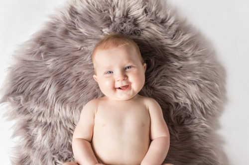 Overhead shot of six month old baby on grey rug smiling up - sitter session aberdeenshire - Debbie Dee Photography