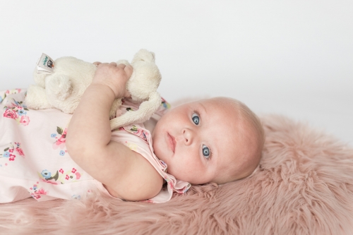 Six month old child laying on pink rug looking to camera holding toy bunny - sitter session aberdeenshire - Debbie Dee Photography