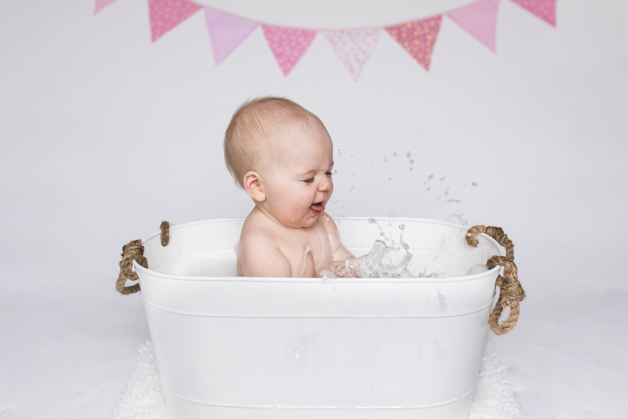 cake smash aberdeen - child laughing and splashing in white splash bath - debbie dee photography